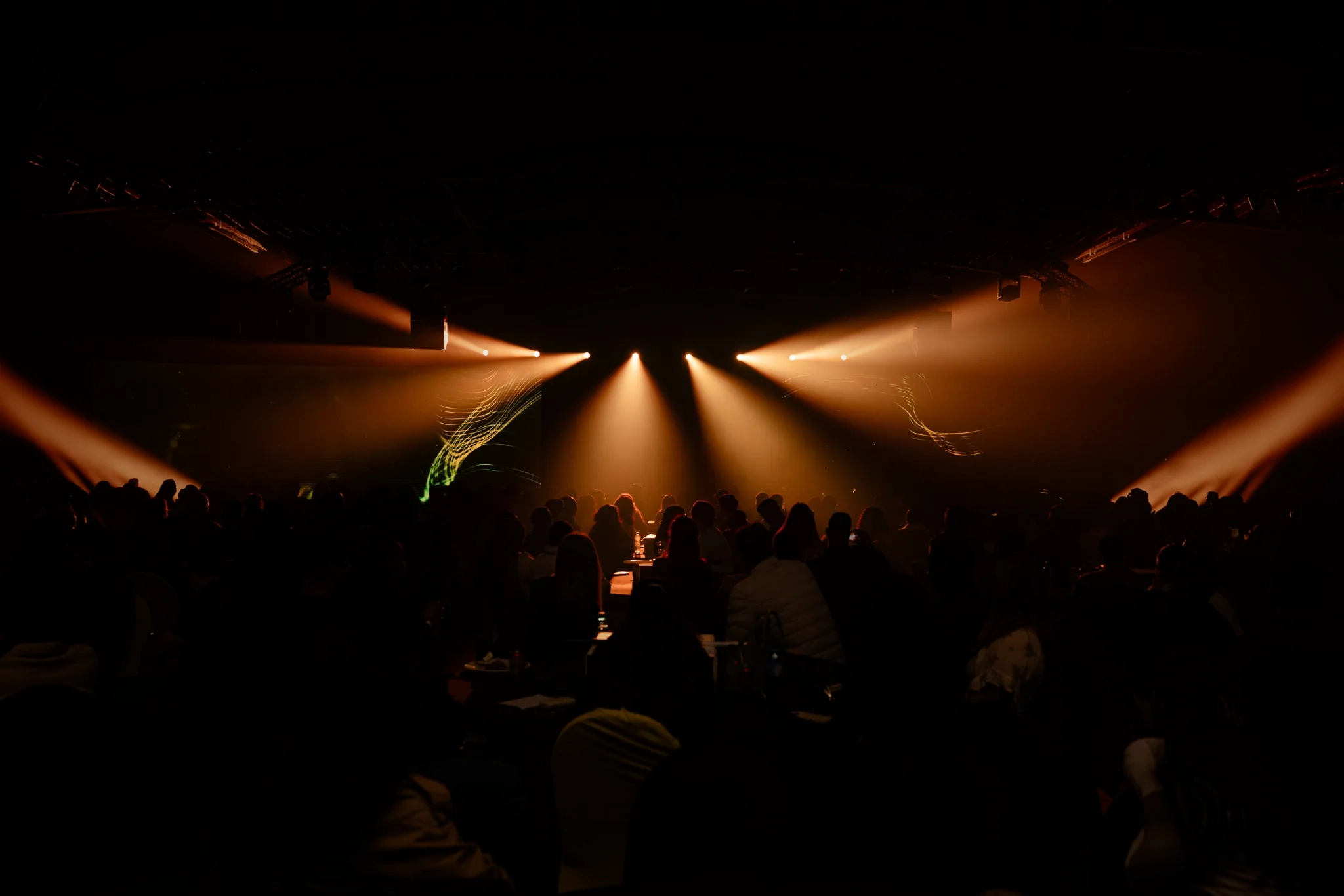 A gala crowd silhouetted under orange stage lighting